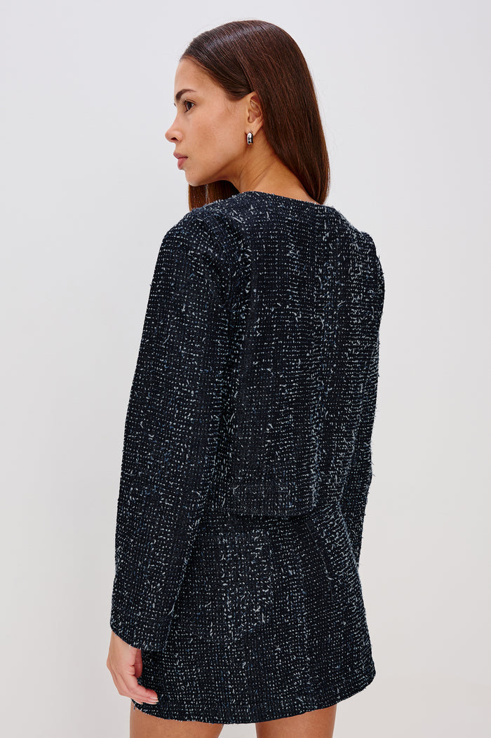 Capistrano Cropped Jacket in Denim Tweed Texture With Crew Neckline, Front Buttons, Buttoned Chest Pockets, and Long Sleeves in Denim Tweed Colorway - Upper Body Back View Featured on Model