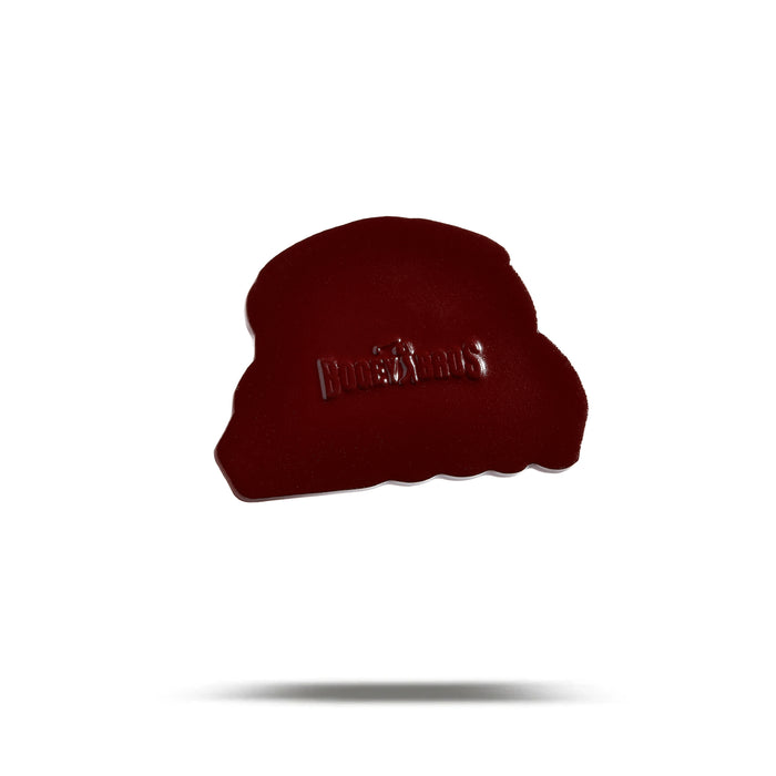 A dark red, irregularly shaped Glizzy Gobbler - Ball Marker with the Honest Kids logo embossed on its surface sits on a plain white background with a faint shadow, resembling a heavy metal ball marker finished in iron nickel plating.