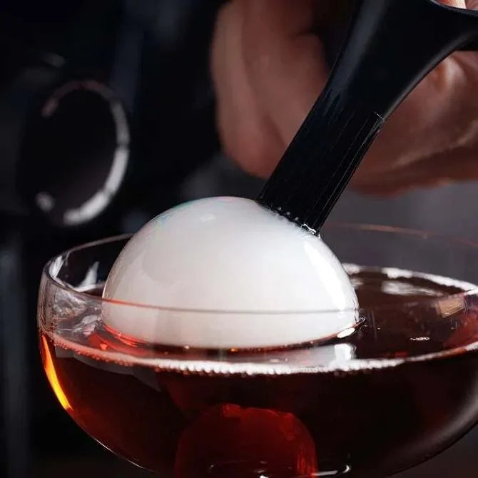 White Smoke Bubble from Breville Commercial Smoke bubble Kit being added to a amber colored cocktail.