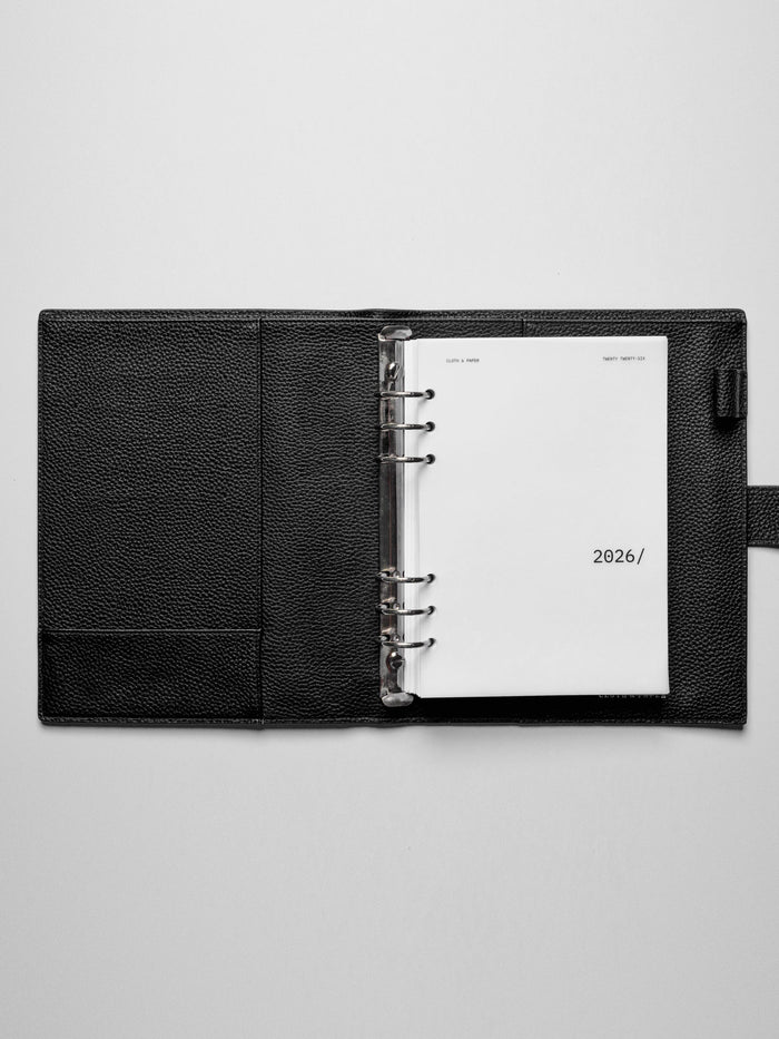 Image shows the 2026 front cover used in a black leather A5 ring-bound planner.