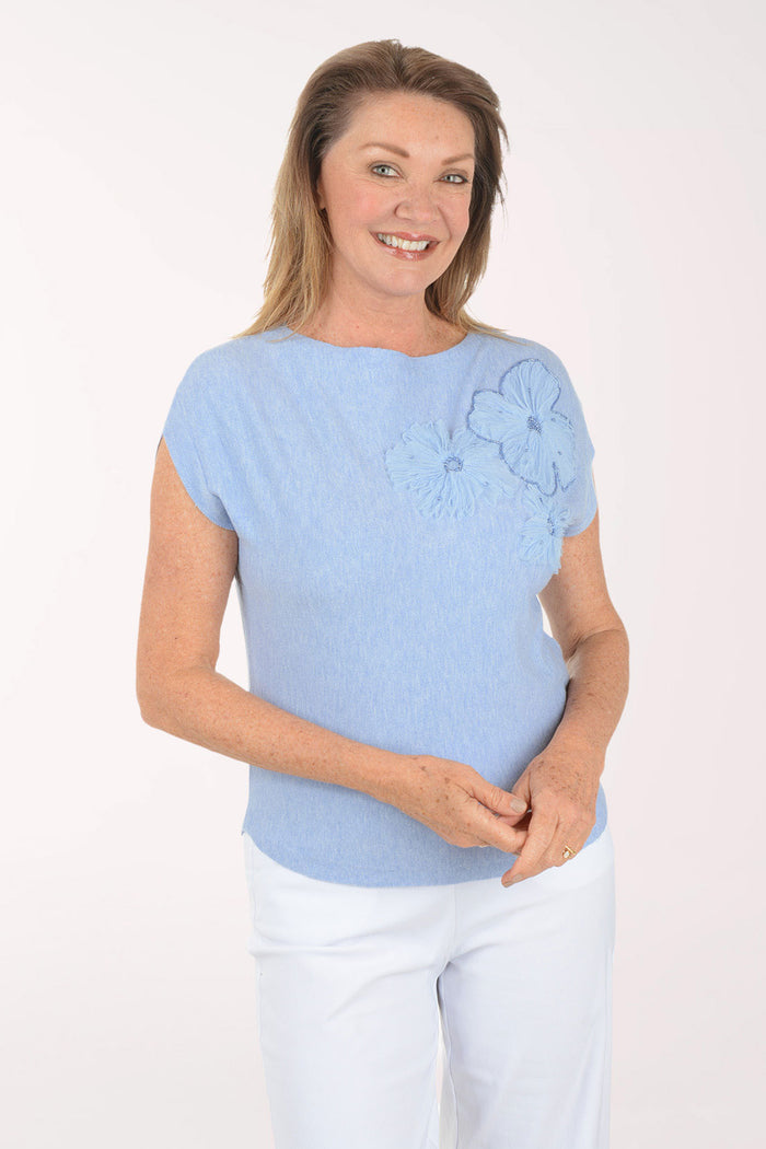 Woman wearing a light blue top with floral designs on a white background