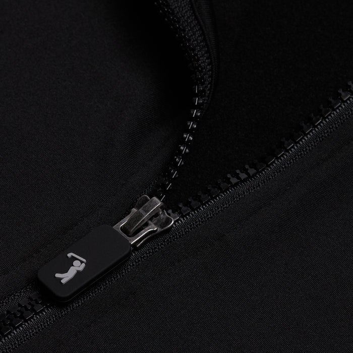 A close-up of the Black - Q-Zip shows a partially unzipped black zipper on smooth, slightly shiny, moisture-wicking fabric. The rectangular pull displays a small white figure icon, possibly swinging a golf club.
