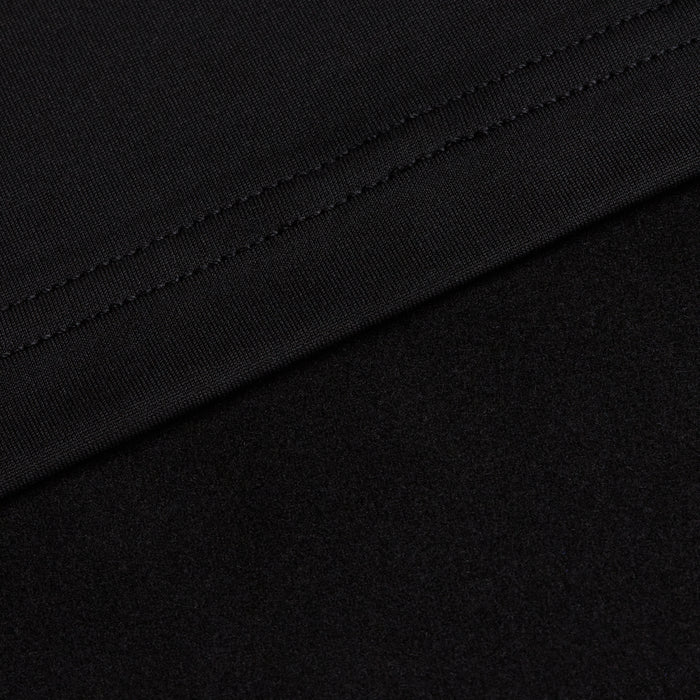 Close-up of Black - Q-Zip showing two black fabrics: the upper section features a stitched seam on smooth, athletic-fit material, while the lower part displays a softer, textured surface. The fabrics meet diagonally across the image.