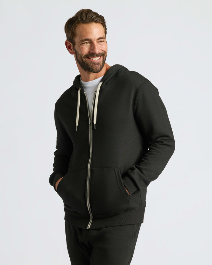Man in Black Fleece French Terry Zip Hoodie, smiling.