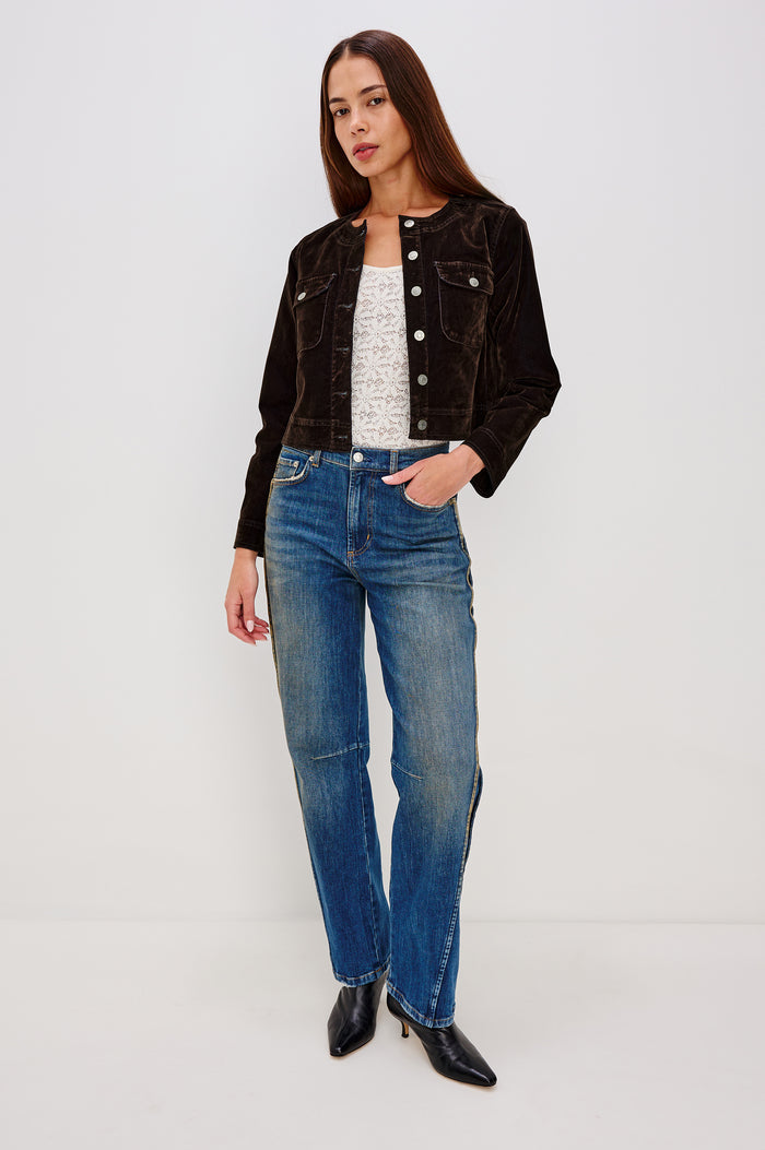 Capistrano Cropped Jacket in Chocolate Velvet Flocked Denim With Crew Neckline, Indigo Wash, Front Buttons, Buttoned Chest Pockets, and Long Sleeves in Chocolate Flocking Colorway - Full Body Front View Featured on Model