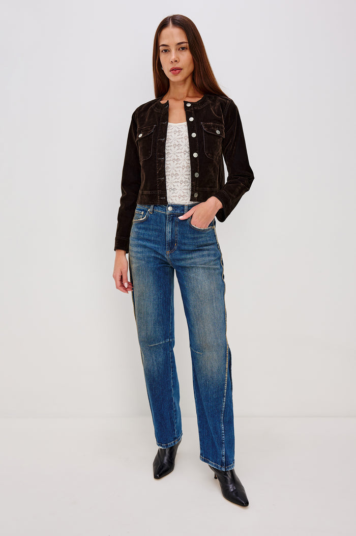 Capistrano Cropped Jacket in Chocolate Velvet Flocked Denim With Crew Neckline, Indigo Wash, Front Buttons, Buttoned Chest Pockets, and Long Sleeves in Chocolate Flocking Colorway - Full Body Front View Featured on Model