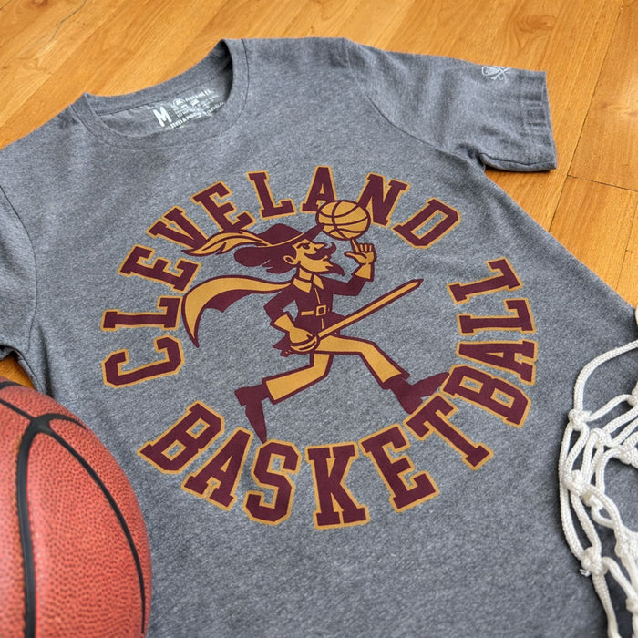 Gray t-shirt with Cleveland Basketball graphic on a wooden floor with basketball and net.