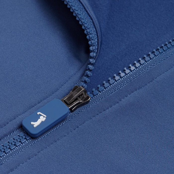Close-up of the Cooler Blue - Q-Zip’s blue zipper and moisture-wicking fabric. The zipper pull shows a white reclining icon. Visible stitching, textured teeth, and an athletic fit deliver comfort and performance.