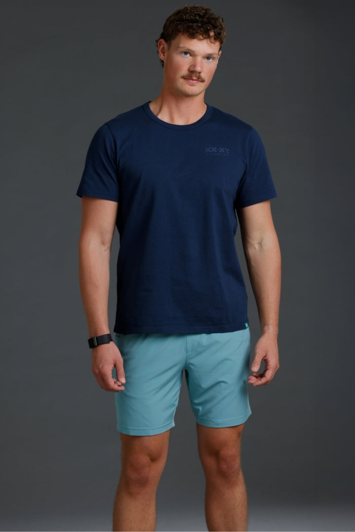 Man wearing a navy t-shirt and light blue shorts on a gray background || Underseas