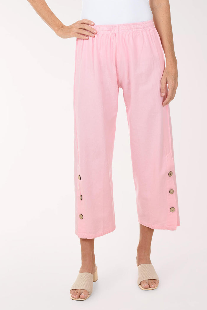 Pink pants with button details worn by a person on a white background