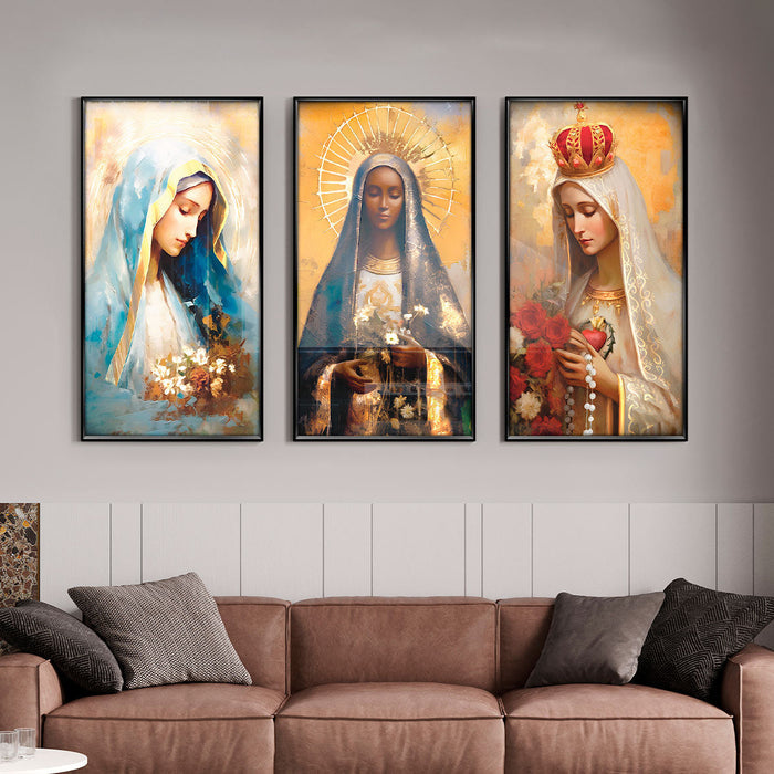 A set of three framed art prints depicting Our Lady of Grace, Our Lady of Fatima, and Our Lady of Aparecida, displayed above a sofa.