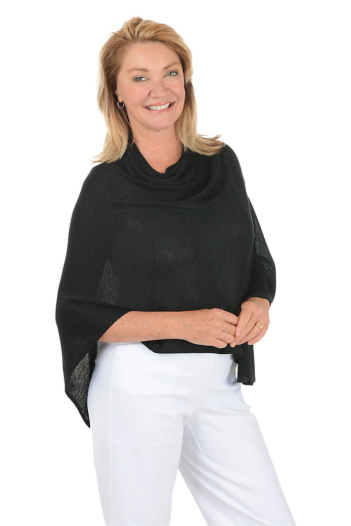 Woman wearing a black poncho over a white outfit on a white background