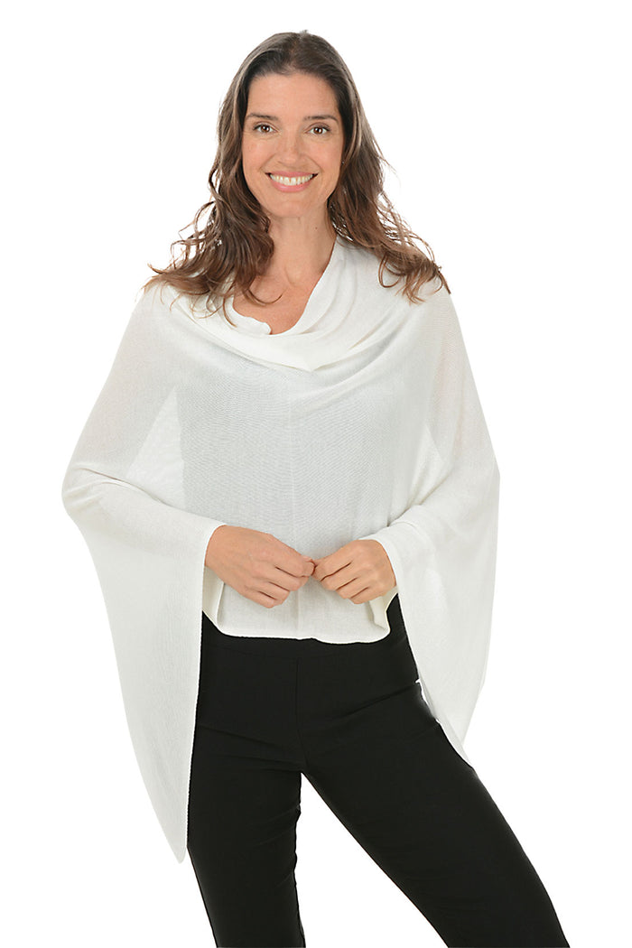 A woman wearing a white bamboo poncho with an asymmetrical hemline, paired with black pants.
