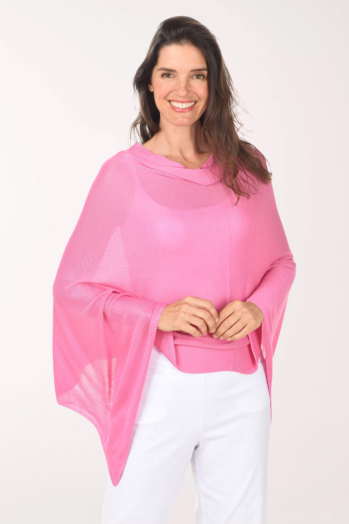 Woman wearing a pink poncho over a white outfit on a white background