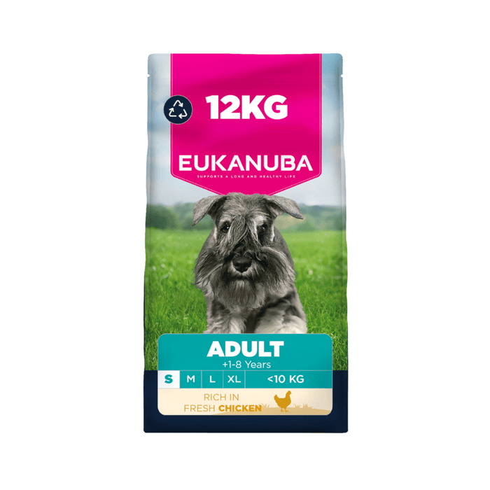 A 12kg bag of Eukanuba Adult dog food for dogs, featuring a Schnauzer on a green grassy field. The packaging has a bright pink top section with white text, a teal band with product details, and a dark blue base.