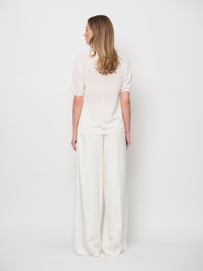 Woman wearing a white outfit against a plain background