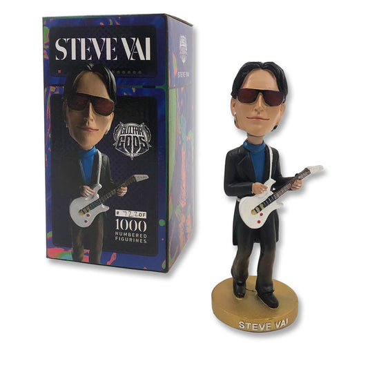 Image of a steve vai bobble head and bobble head box against white background. The bobble head is steve vai wearing black sunglasses and wearing black pants and a jacket with a blue shirt. he holds a white guitar. the stand says steve vai in white text. the box says steve vai in white text across the top and shows a photo of the bobble head.