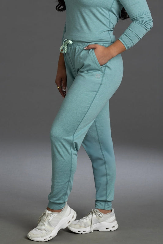 Person wearing a teal tracksuit with white sneakers on a gray background || Underseas