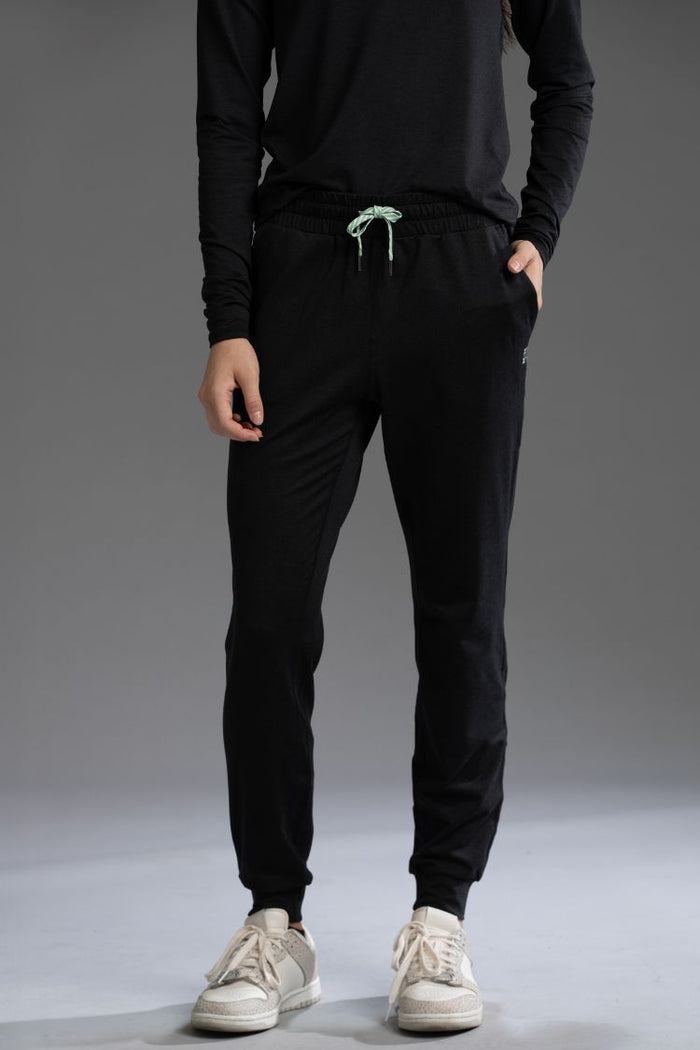 Person wearing black jogger pants and white sneakers on a gray background || black