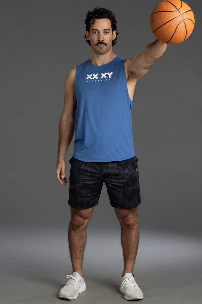 Man holding a basketball wearing a blue tank top with 'XX-XY' branding on a gray background || Black Camo