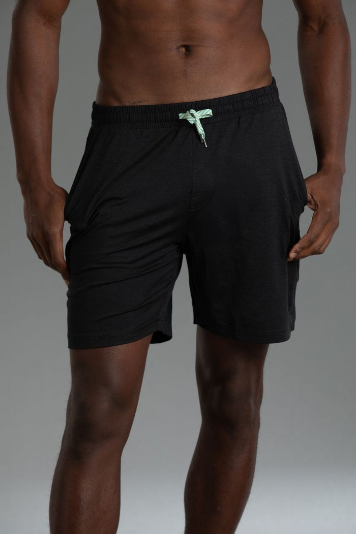 Black athletic shorts with a green drawstring on a gray background || black