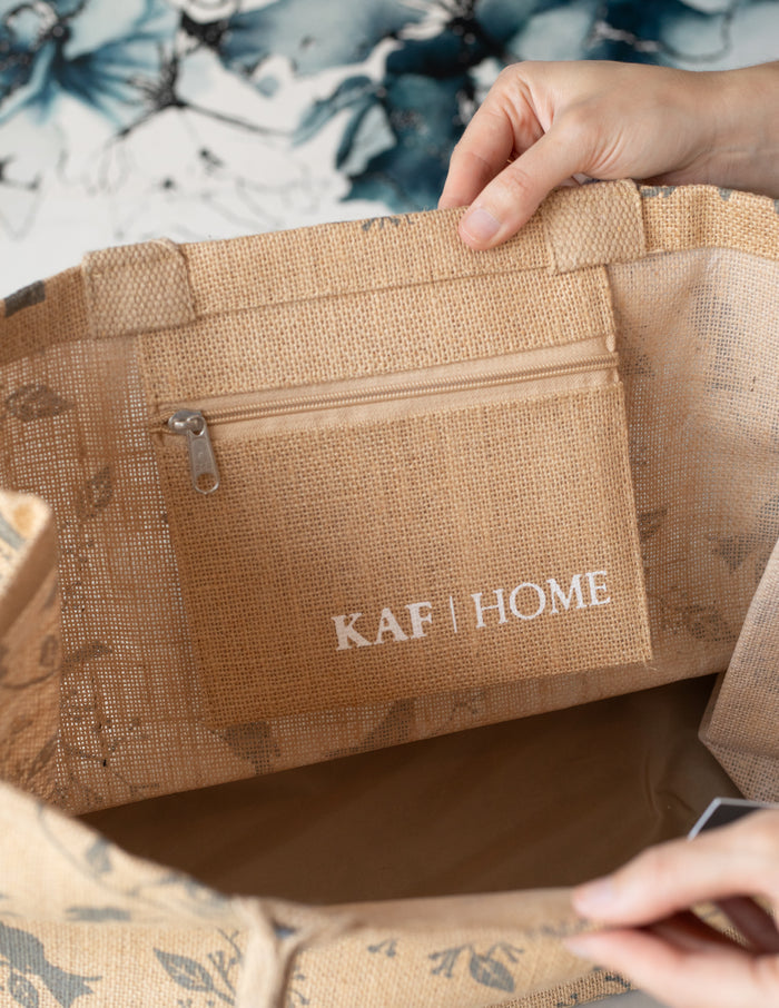 Inside of a beige jute tote bag with a bird print, showing the KAF HOME logo.