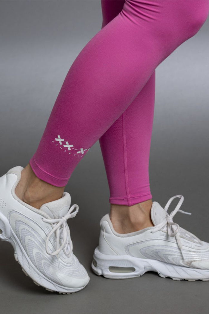 Person wearing pink leggings and white sneakers on a gray background || Bright Fuchsia