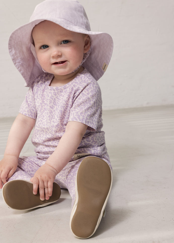 Baby wearing a purple leopard set and summer hat