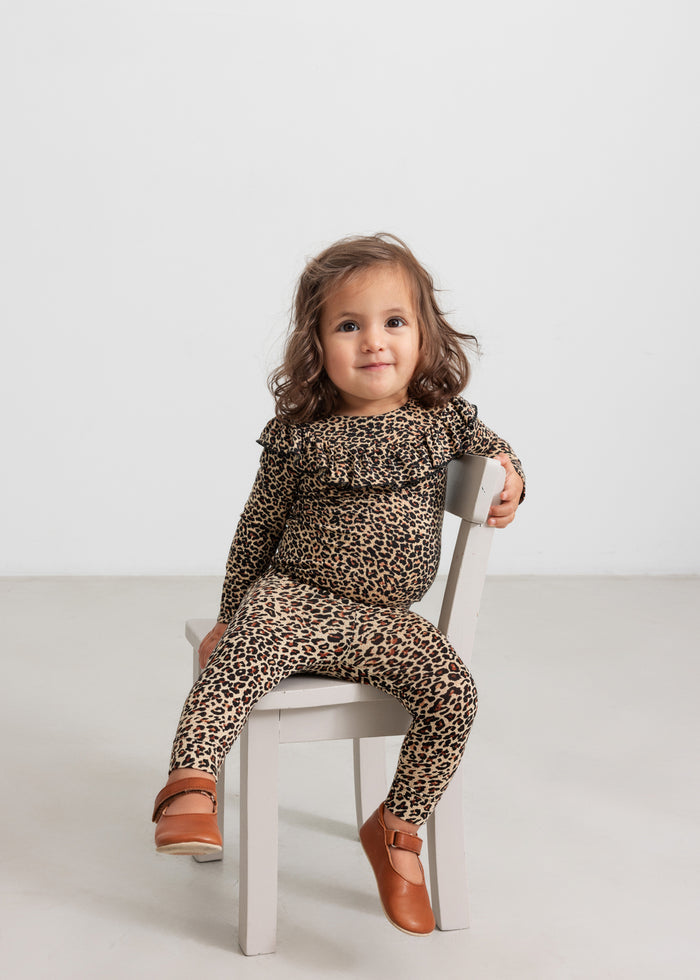 Little girl in leopard leggings and bodysuit with a frill