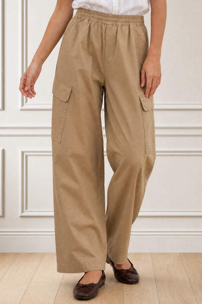 Close-up crop of a model wearing the Aspiga Matcha Trousers in Camel, showing the elasticated waist and cargo pockets