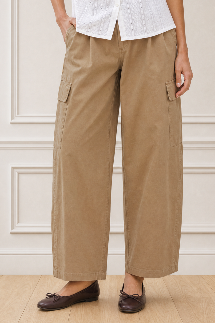 Close-up crop of a model wearing the Aspiga Matcha Trousers in Camel with a white blouse, showing the cargo pocket