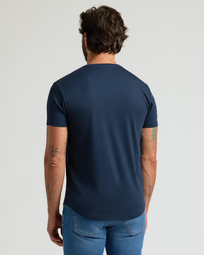 Man wearing a navy blue Pima Cotton Blend Curved Hem Crew 4-Pack t-shirt viewed from the back, paired with blue jeans, showcasing a casual men's basics style.