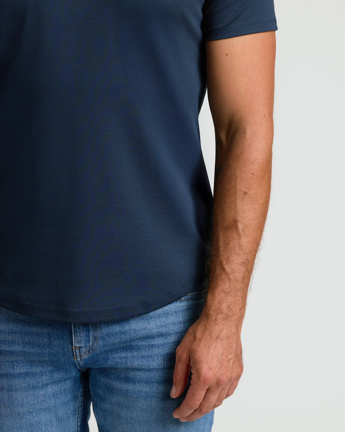Close-up of a man wearing a Navy Pima Cotton Blend Curved Hem Crew paired with blue jeans, showcasing the curved hem and smooth cotton blend fabric in a casual style.