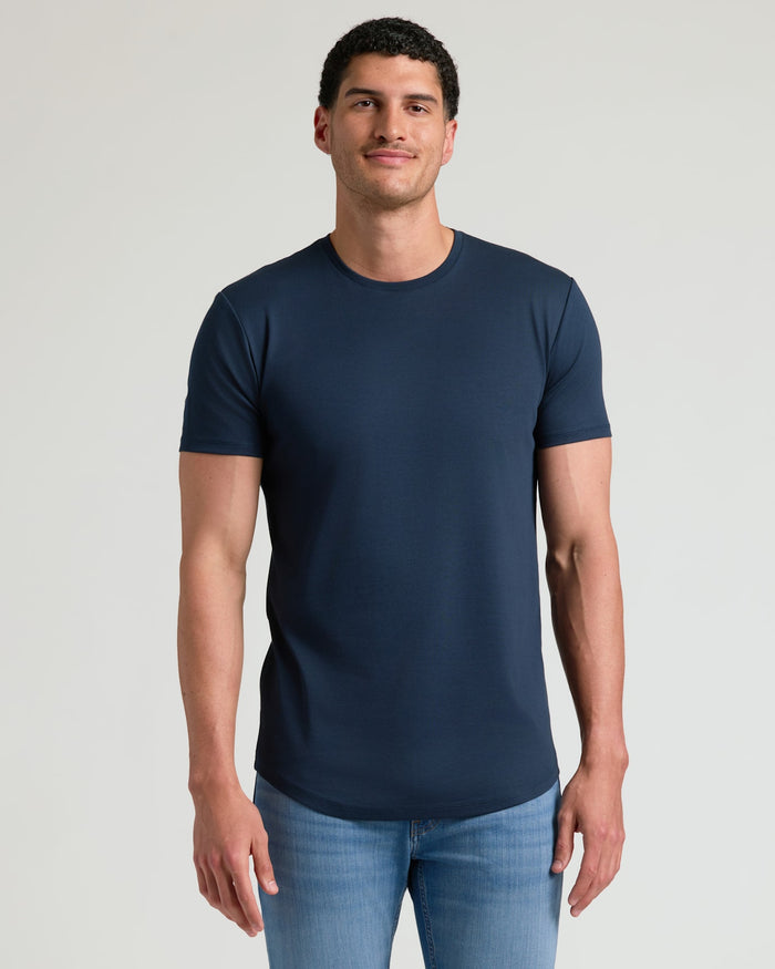 Man wearing a navy Tall Pima Cotton Blend Curved Hem Crew 4-Pack t-shirt paired with light blue jeans, showcasing a clean, fitted men's basics style.