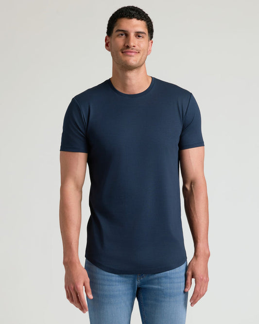 Man wearing a navy Tall Pima Cotton Blend Curved Hem Crew 4-Pack t-shirt paired with light blue jeans, showcasing a clean, fitted men's basics style.