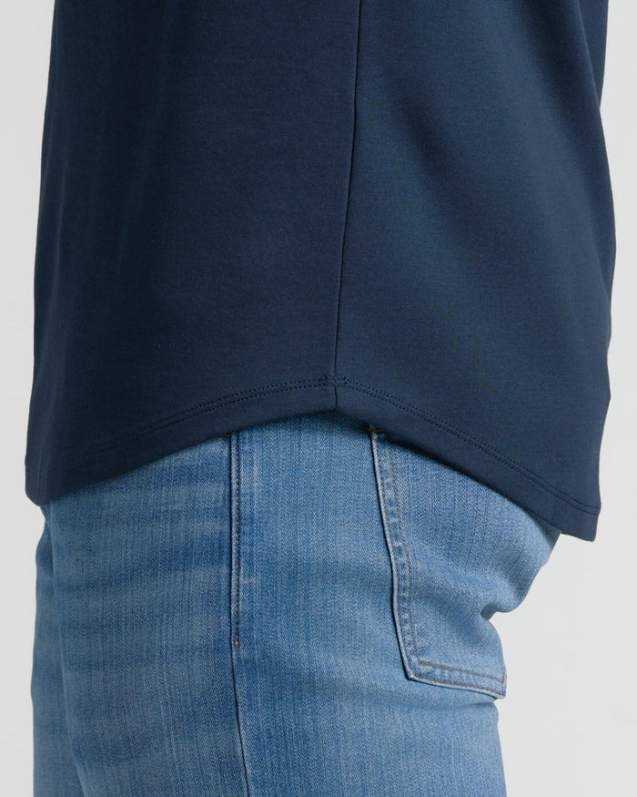 Close-up of the curved hem detail on the Navy Tall Pima Cotton Blend Curved Hem Crew worn over light blue denim jeans, highlighting the smooth fabric and tailored fit.