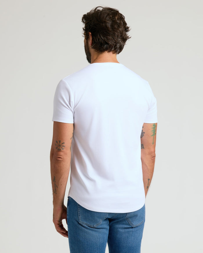 Man seen from behind wearing a white Pima Cotton Blend Curved Hem Crew 7-Pack t-shirt paired with blue jeans, showcasing a casual men's basics style.