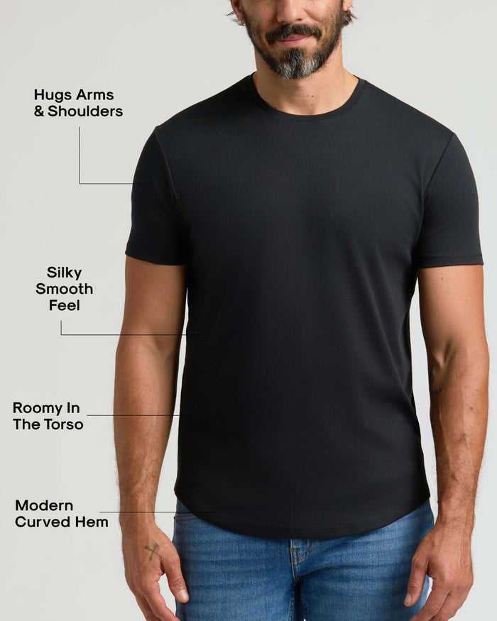 Man wearing a black Pima Cotton Blend Curved Hem Crew 4-Pack shirt, highlighting a modern curved hem, roomy torso, silky smooth feel, and snug fit around arms and shoulders.