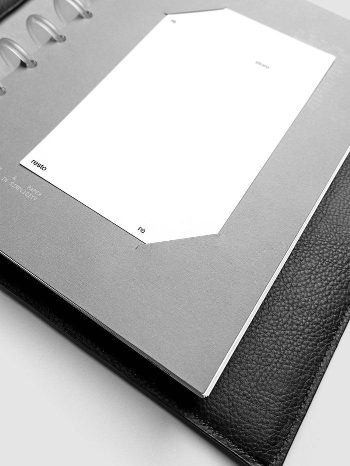 Close up view of a grey cardstock planner dashboard with white plastic card inserted in slits with white printed text.