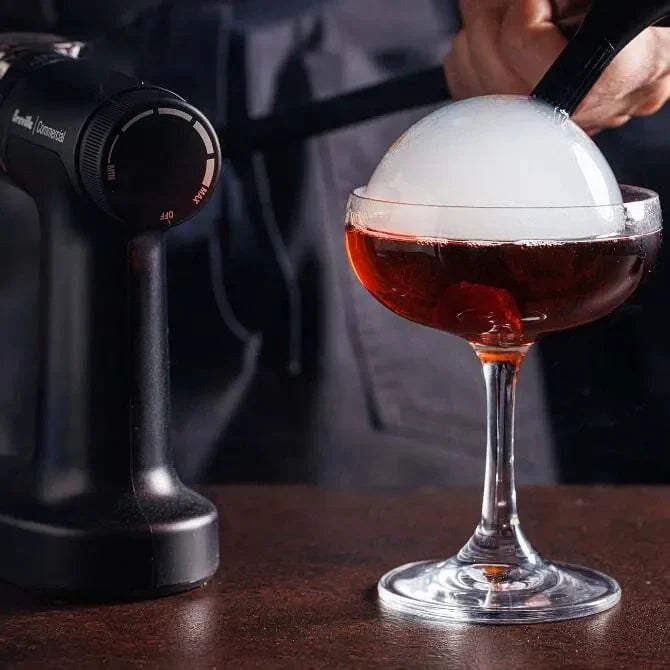 Cocktail with a large smoke bubble being added using a Breville Commercial Smoke Bubble Kit.
