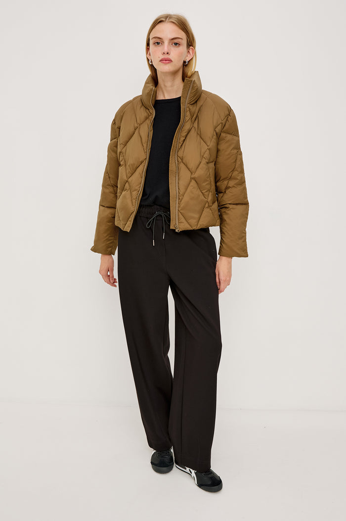 Summit Cropped Puffer Jacket With Stand Collar, Front Zipper, Quilted Detailing, Side Pockets, Tonal Branded Stamp, and Long Sleeves in Ginger Colorway - Full Body Front View Featured on Model