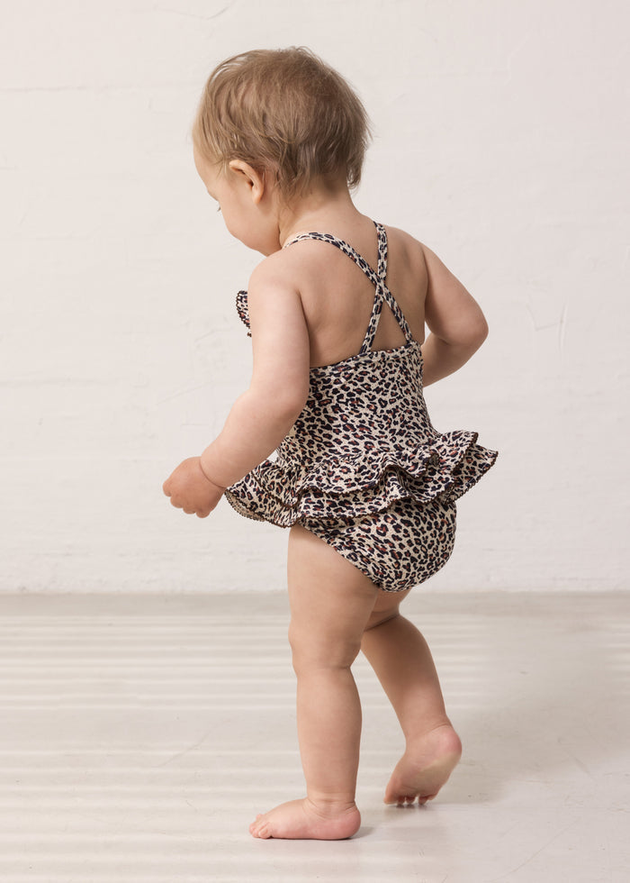 Brown leopard‑patterned swimsuit with cross straps and ruffles.