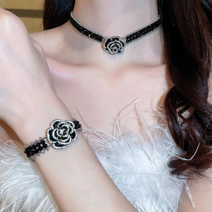 Alloy flower statement necklace and matching bracelet in black and silver worn with white feather top