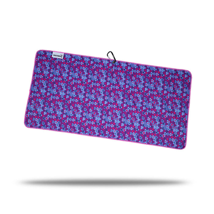The Whale Tail - Towel is a rectangular microfiber towel with a vibrant geometric pattern in purple, blue, and pink tones, finished with a solid pink border. It features a small white label, black clip and eyelet on one corner, shown against a white background.