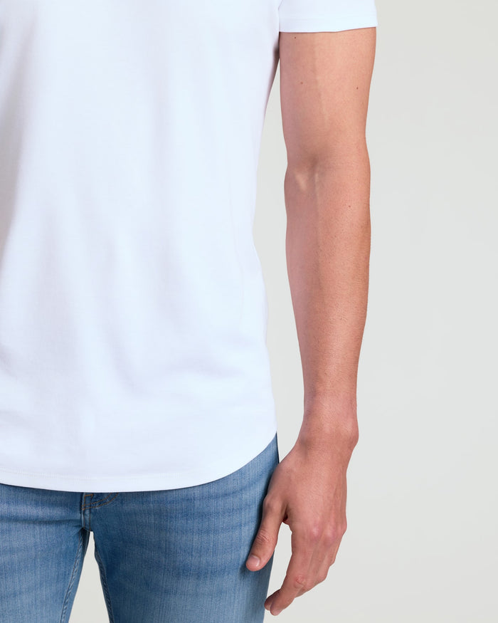 Close-up of a man wearing a white Tall Pima Cotton Blend Curved Hem Crew 7-Pack shirt paired with blue jeans, showcasing the curved hem detail and smooth cotton blend fabric.