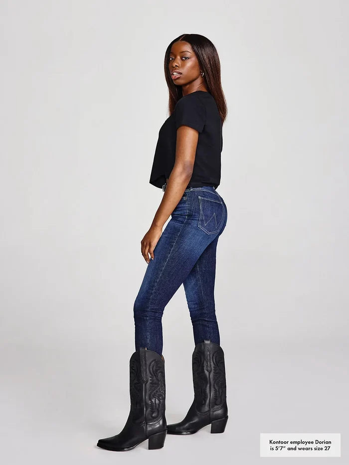 Woman in black top, blue jeans, and black boots.